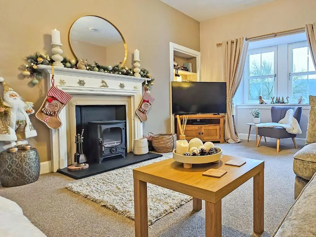 a living room with a fireplace and a tv at Balmore Farmhouse in Lochend