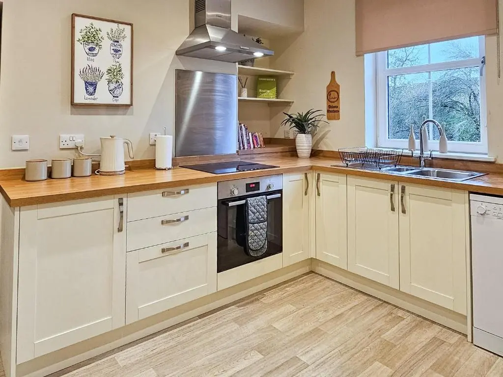 a kitchen with white cabinets and a sink at Balmore Farmhouse in Lochend