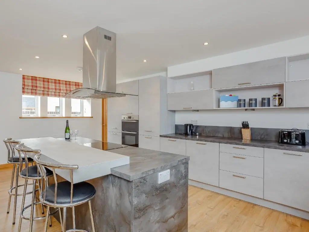 a kitchen with white cabinets and a counter with bar stools at Auld Kirk Hall in Kirktown of Auchterless