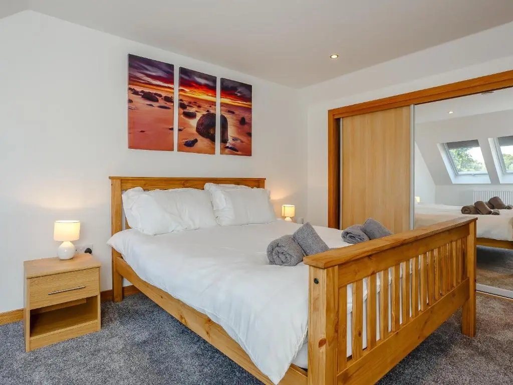 a bedroom with a large wooden bed with white sheets at Auld Kirk Hall in Kirktown of Auchterless
