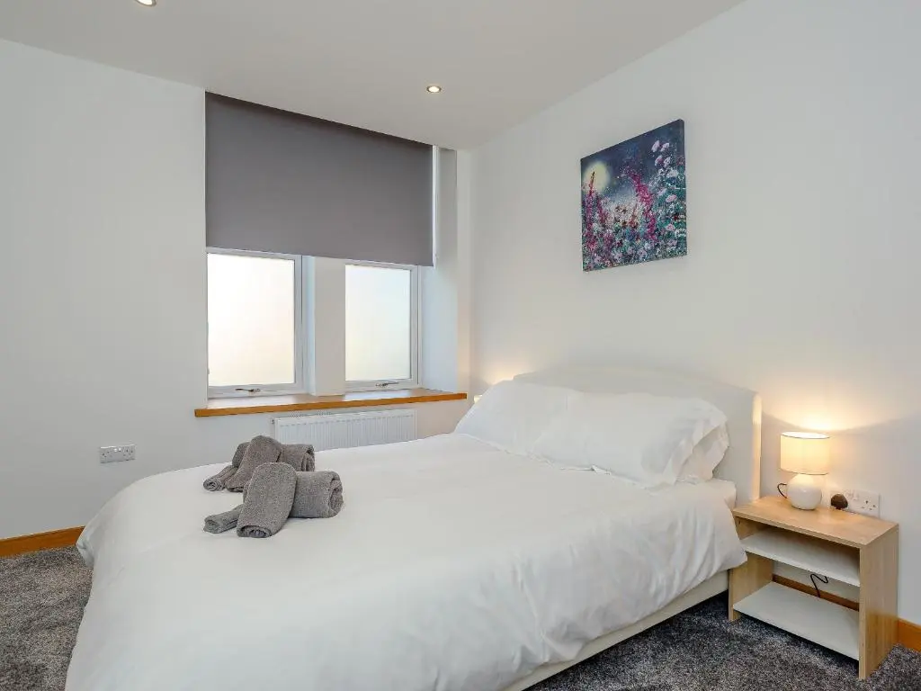 a bedroom with a white bed with a stuffed animal on it at Auld Kirk Hall in Kirktown of Auchterless