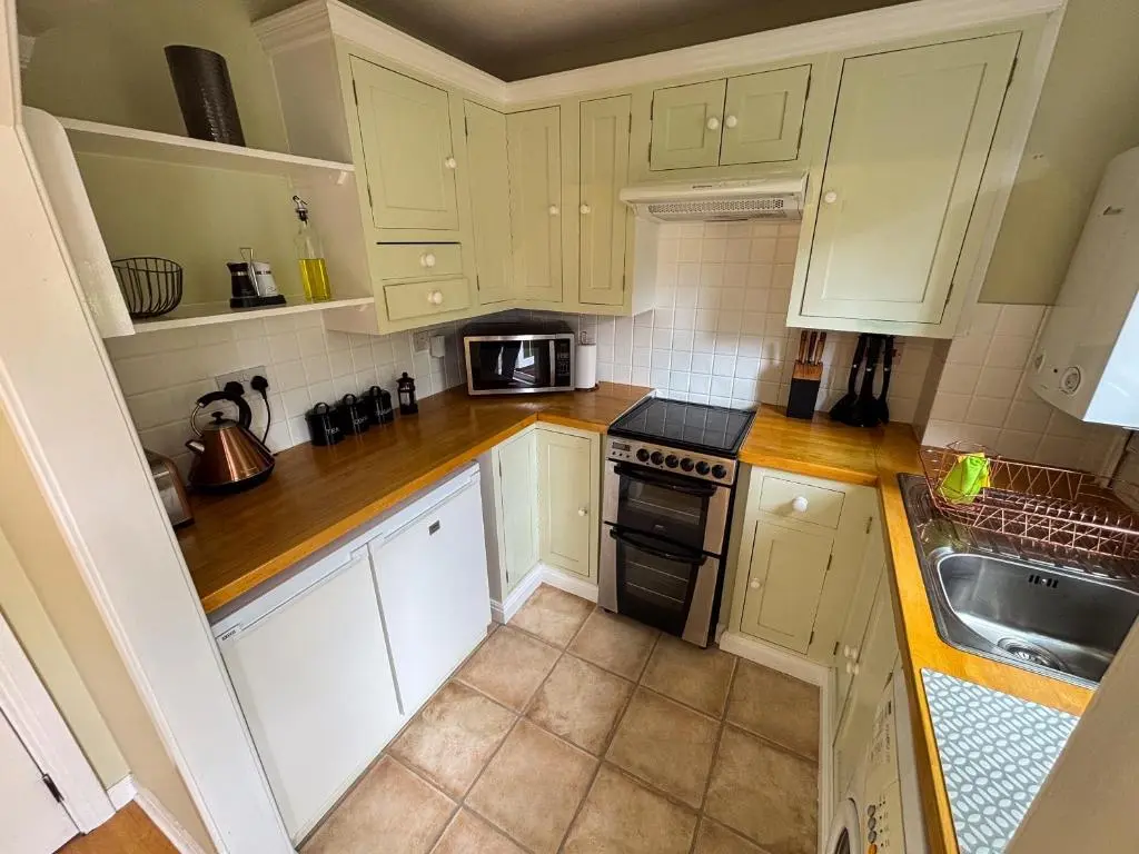 a small kitchen with white cabinets and a sink at Inverness Holiday Retreat - 2 Bedroom in Inverness