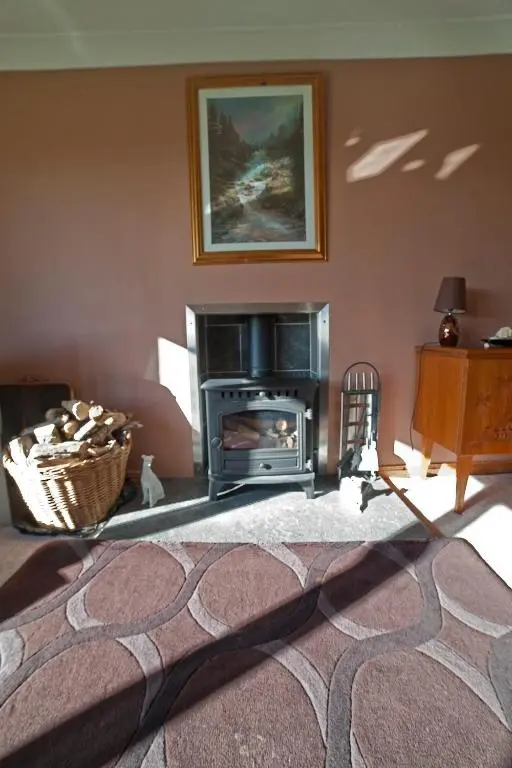 a living room with a fireplace and a stove at Ard Garraidh in Ardersier