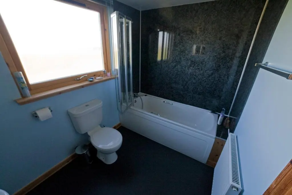a bathroom with a toilet and a tub and a window at Ard Garraidh in Ardersier