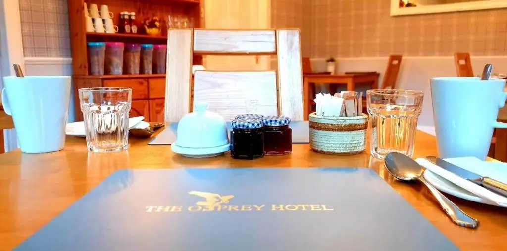 a wooden table with glasses and a napkin on it at The Osprey Hotel in Kingussie