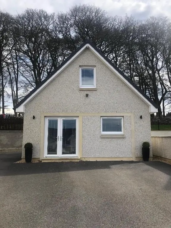 a white house with two windows on a driveway at Appin Apartment in Inverness