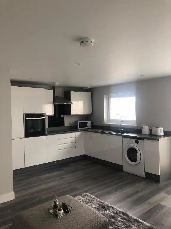 a kitchen with white cabinets and a washing machine at Appin Apartment in Inverness