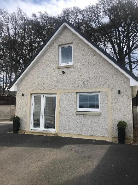 a white house with two windows on a street at Appin Apartment in Inverness