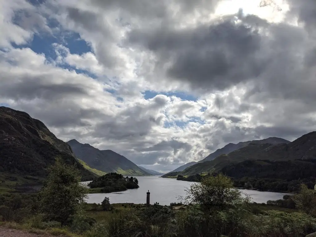 a river in the middle of a valley with mountains at Wee Wilds in Newtonmore