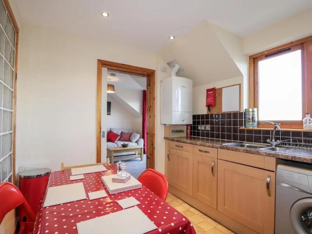 a kitchen with a table and red chairs in it at Riverview Apartment in Inverness