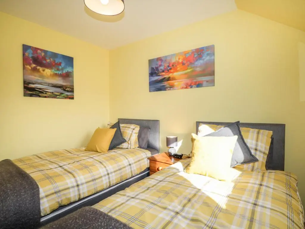 a bedroom with two beds and two paintings on the wall at Riverview Apartment in Inverness