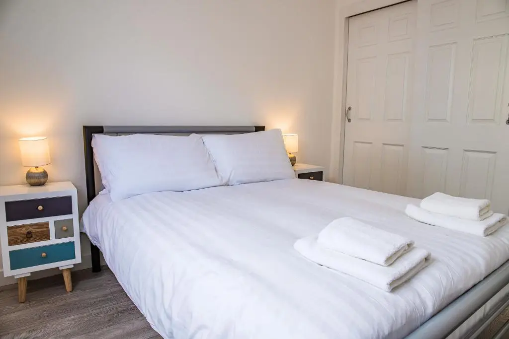 a bedroom with a white bed with two towels on it at Millburn Apartment in Inverness