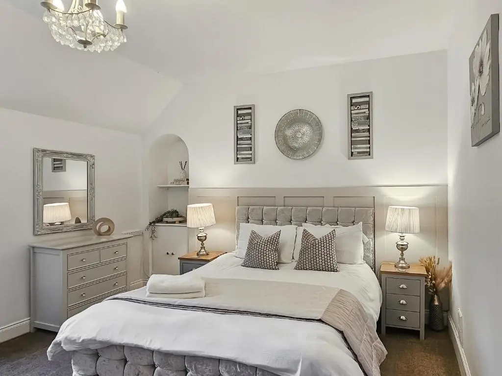 a white bedroom with a large bed with two night stands at Antfield House in Lochend