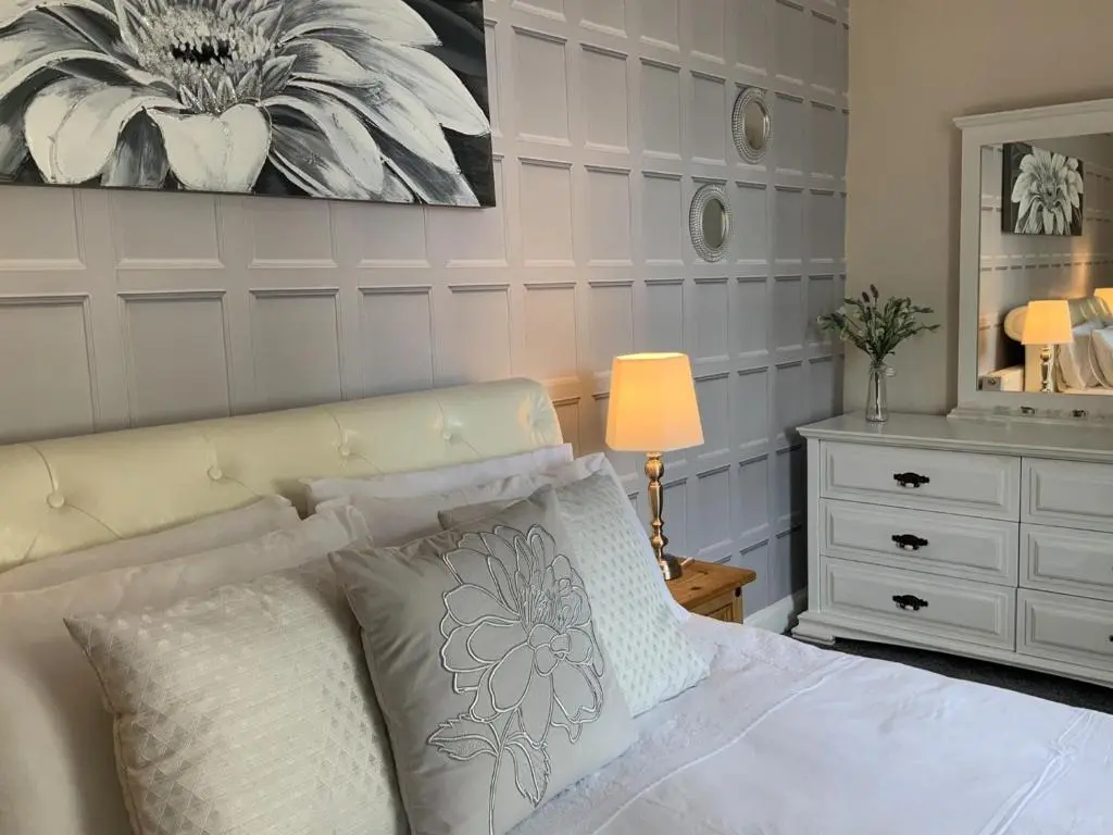 a bedroom with a white bed and a dresser at Antfield House in Lochend