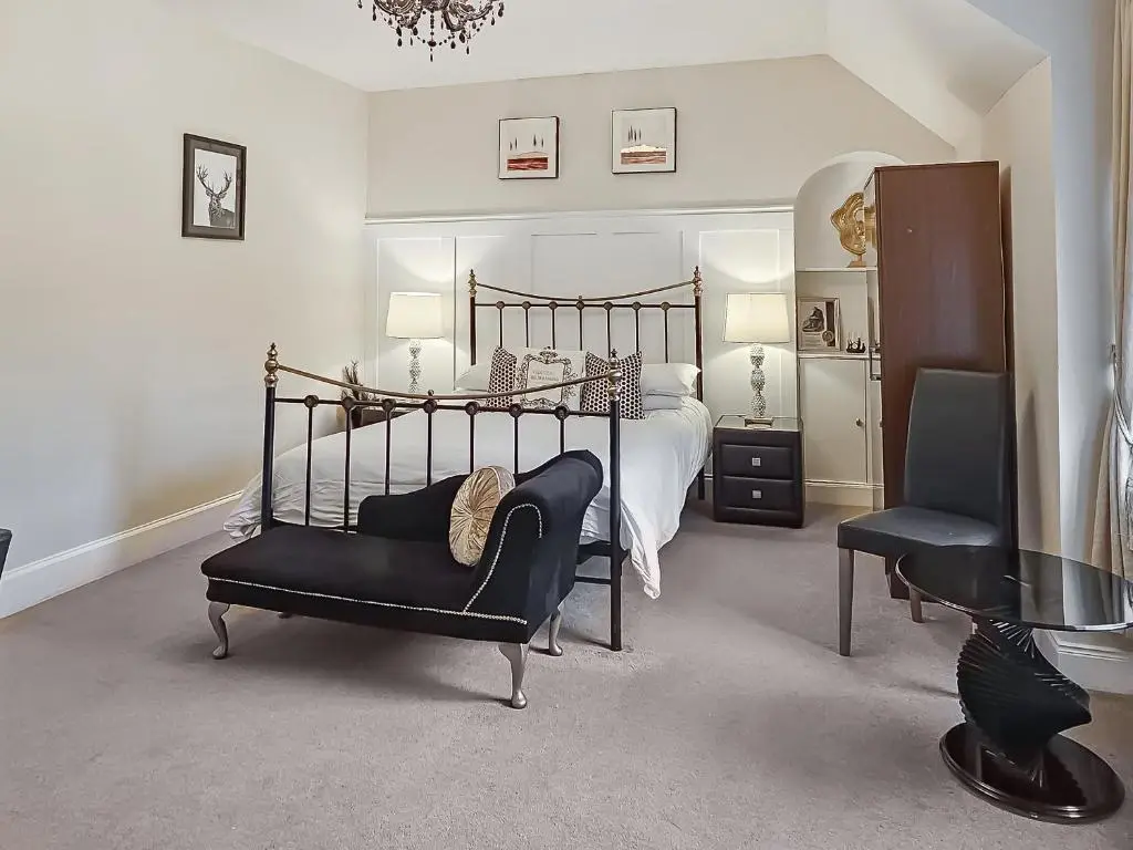 a bedroom with a bed and a chair and a table at Antfield House in Lochend