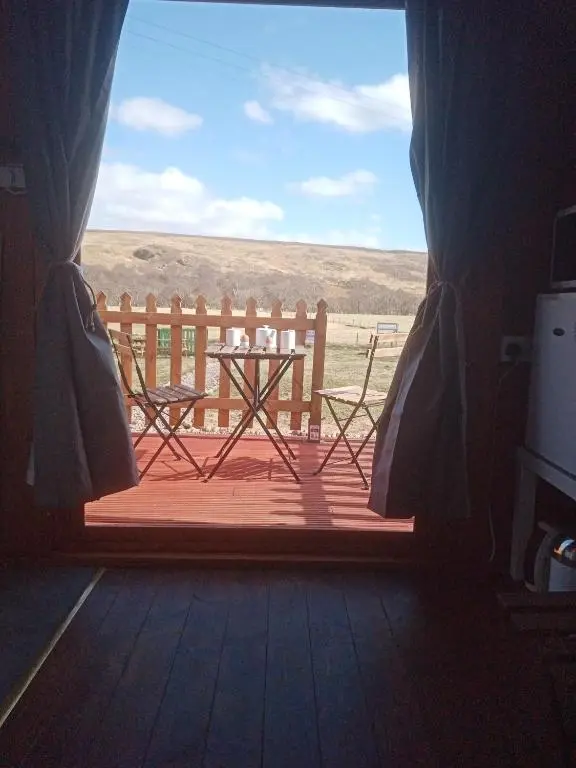a view of a table and a bench from a window at Wee Hoose Glamping Pod 1 in Skail