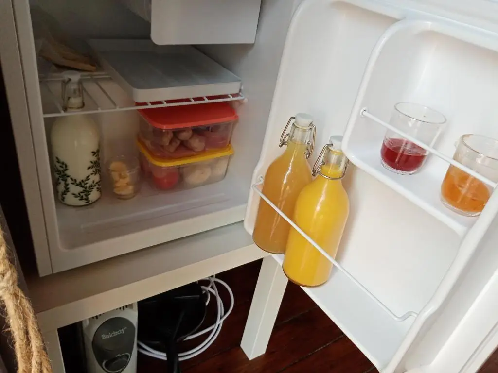 an open refrigerator with two bottles of orange juice at Wee Hoose Glamping Pod 1 in Skail