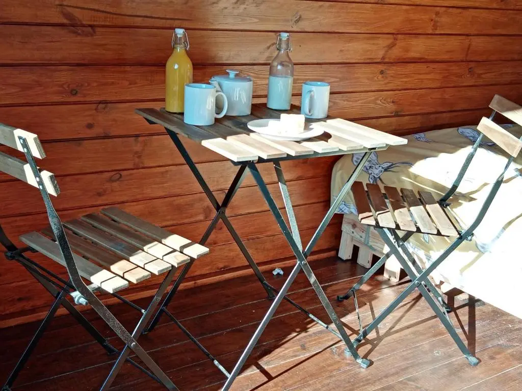 a table with two chairs and two bottles of wine at Wee Hoose Glamping 3 in Kinbrace