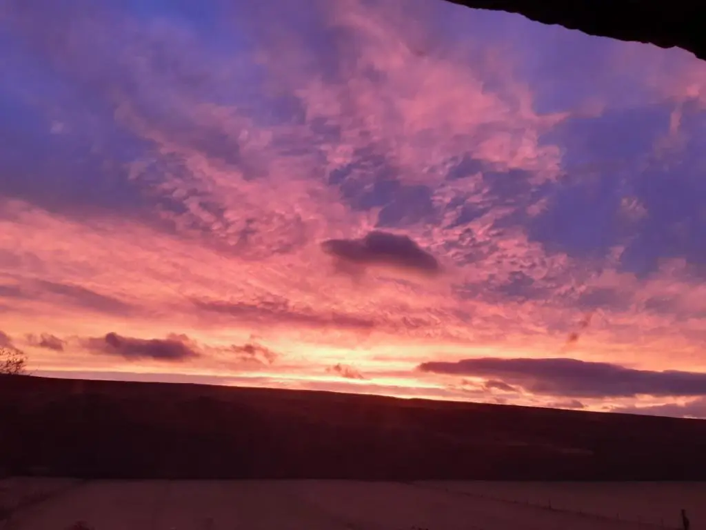 a sunset in the sky over a building at Wee Hoose Glaping Pod 2 in Skail