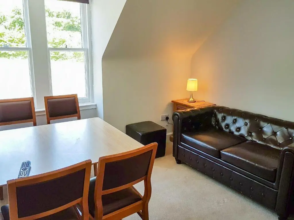 a living room with a table and a leather couch at The Red Kite - Uk31003 in Avoch