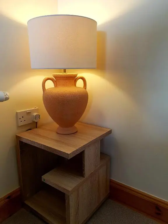 a vase sitting on a wooden shelf with a lamp at Caledonian 2 bedroom free parking in Inverness