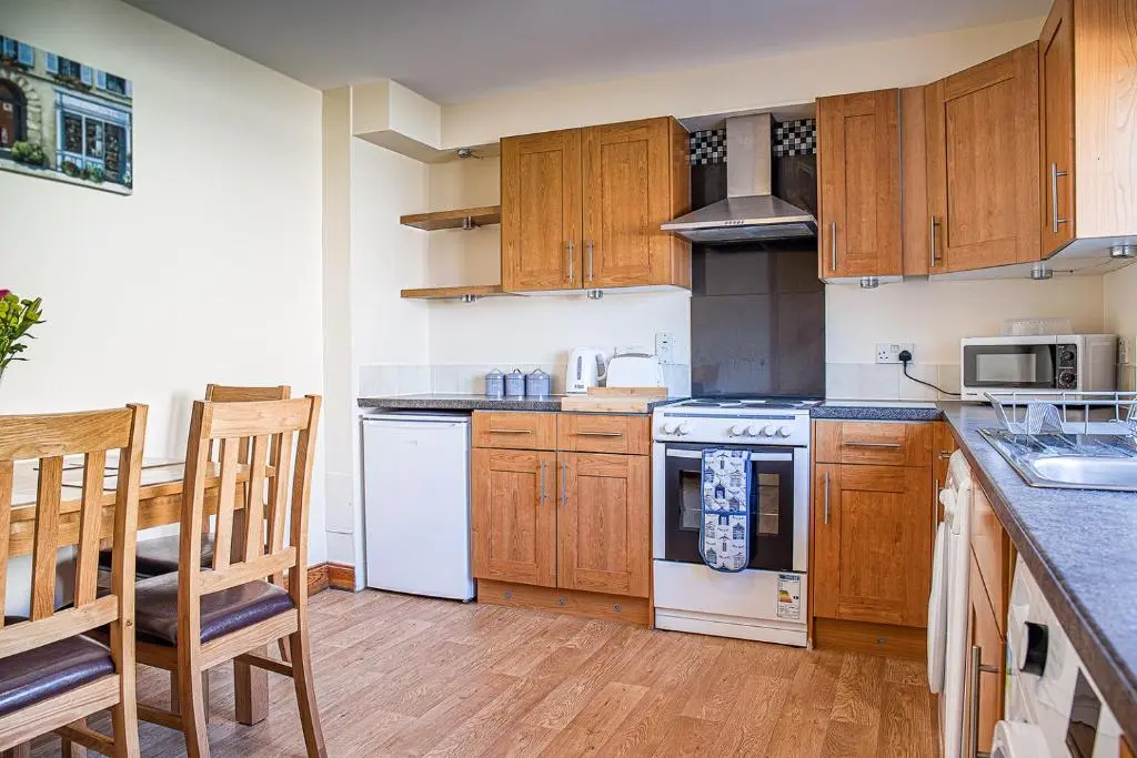 a kitchen with white appliances and wooden cabinets at Caledonian 2 bedroom free parking in Inverness
