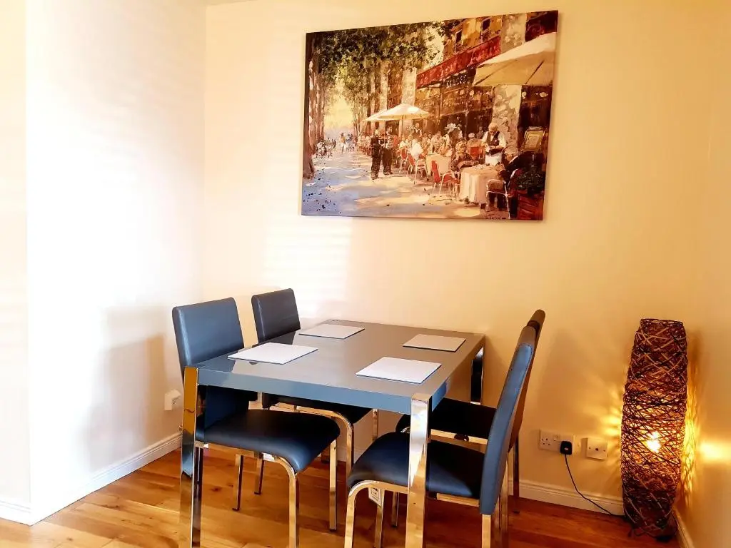 a dining room table with chairs and a painting on the wall at Inverness City 2 bedroom free parking in Inverness