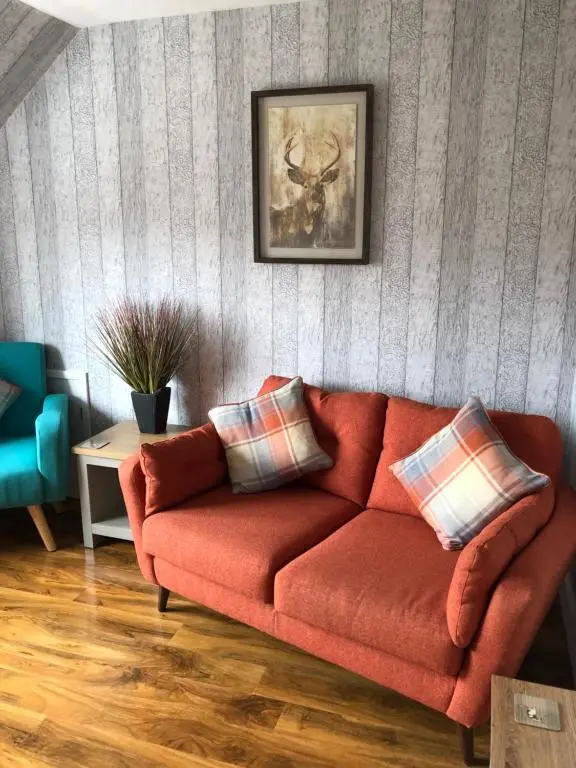 a living room with a red couch with two pillows at Thistle Apartment, Inverness in Inverness