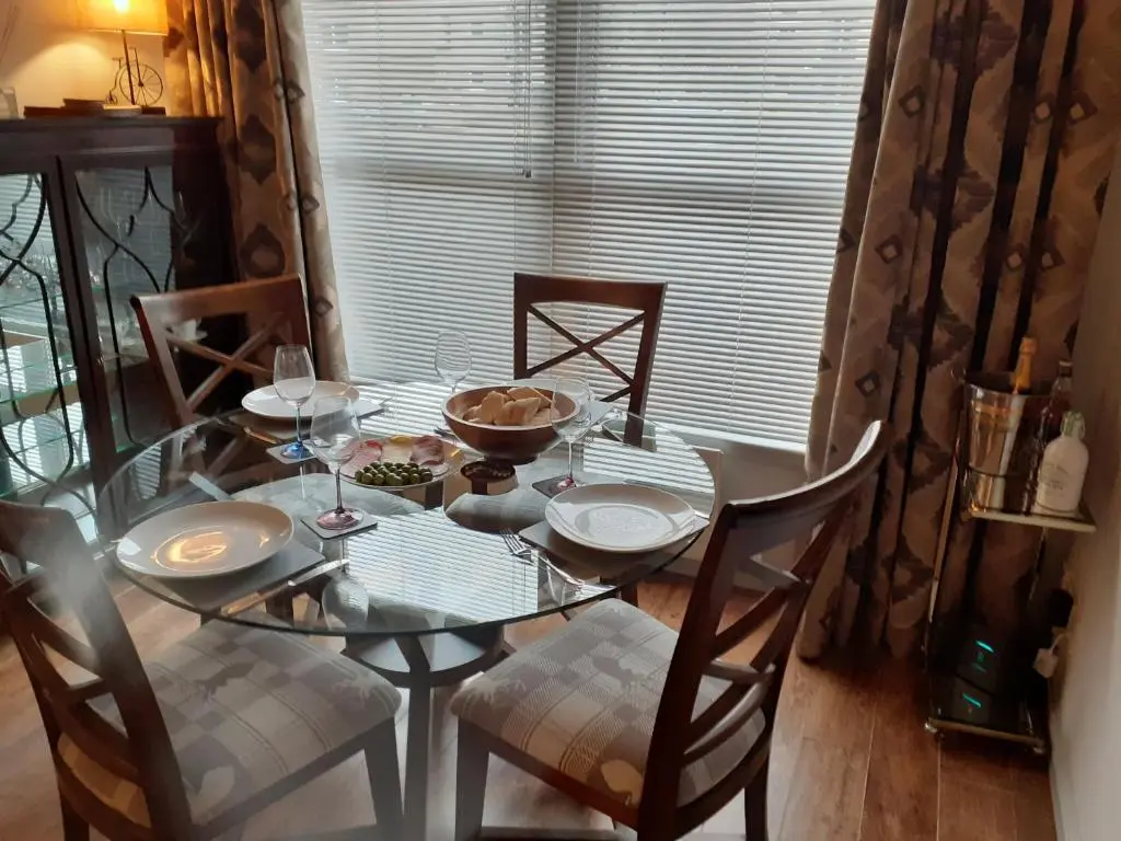 a dining room table with chairs and a glass table and chairsktop at Bishops Park Apartment in Inverness