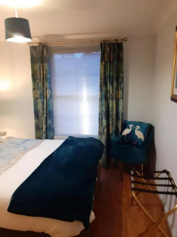 a bedroom with a bed and a chair and a window at Bishops Park Apartment in Inverness