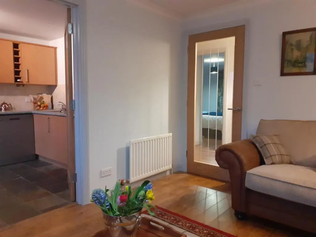 a living room with a couch and a kitchen at Bishops Park Apartment in Inverness