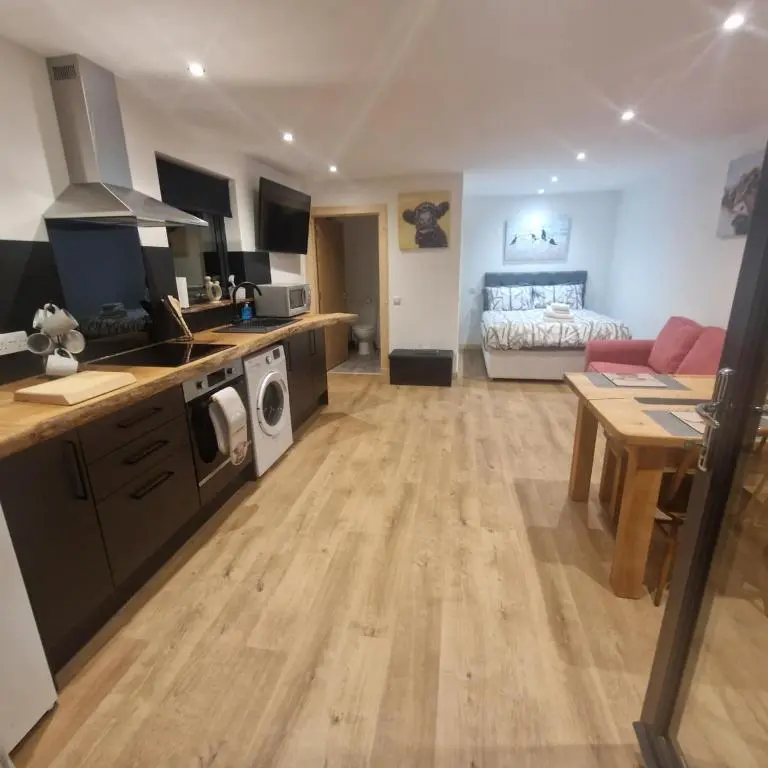 a large kitchen and living room with a bed at Pleasant Point Holiday Cottages in Rosemarkie