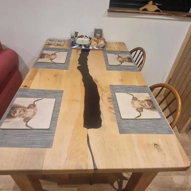 a wooden table with four pictures of a cat on it at Pleasant Point Holiday Cottages in Rosemarkie