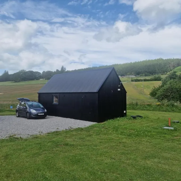 a black building with a car parked next to it at Pleasant Point Holiday Cottages in Rosemarkie
