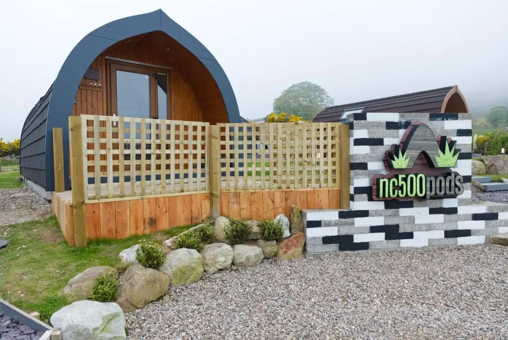 a small house with a fence and a sign at North Coast 500 Pods - Brora in Brora
