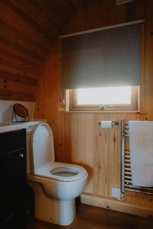 a bathroom with a white toilet in a wooden room at North Coast 500 Pods - Brora in Brora