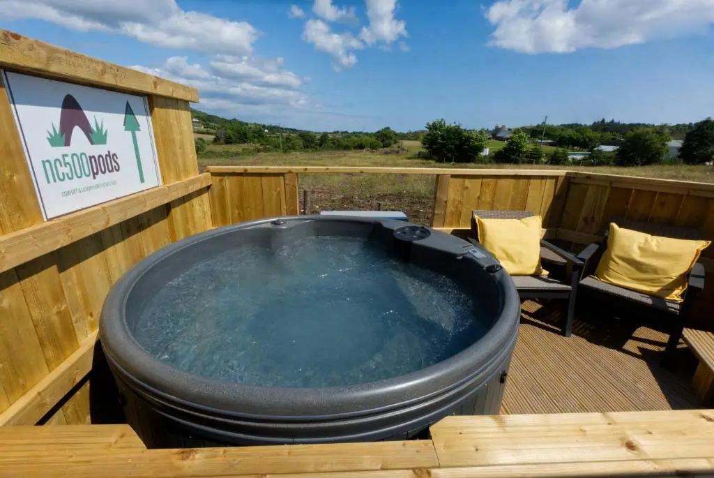 a hot tub on a deck with a table and chairs at North Coast 500 Pods - Brora in Brora