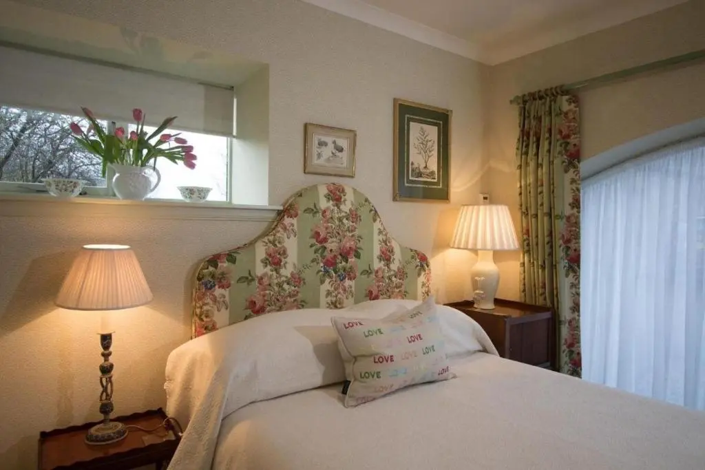 a bedroom with a bed with two lamps and a window at Balnagown Estates Peat Cottage in Kildary