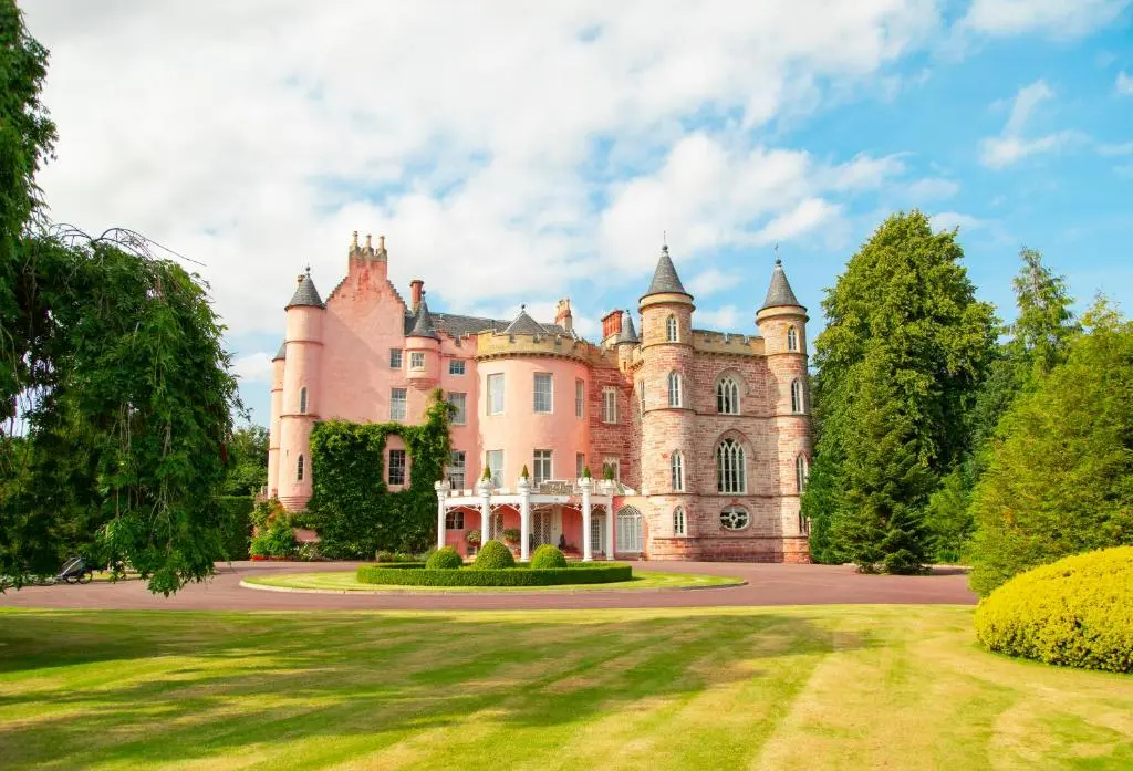 an old castle with a lawn in front of it at Balnagown Estates Peat Cottage in Kildary