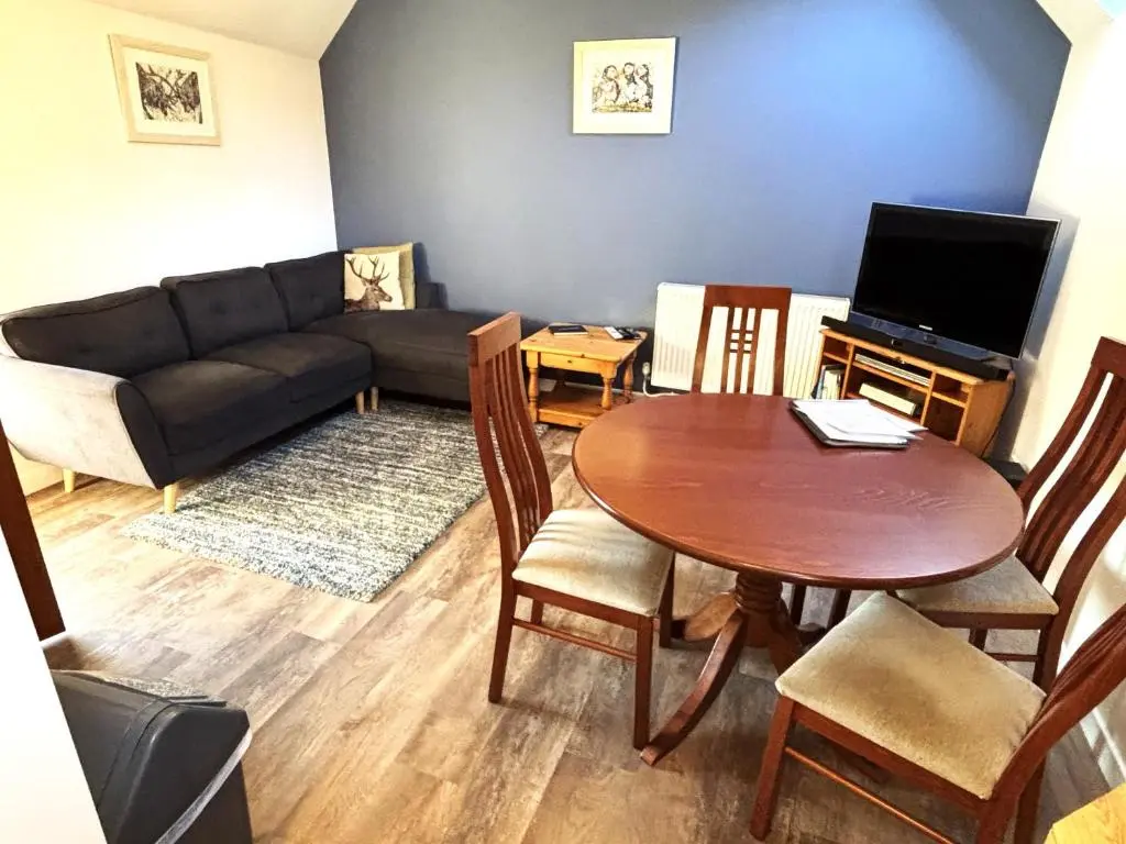 a living room with a table and a couch at Easter Corrie Cottages in Ballindalloch