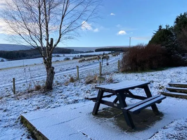 a picnic table in the snow next to a field at Easter Corrie Cottages in Ballindalloch