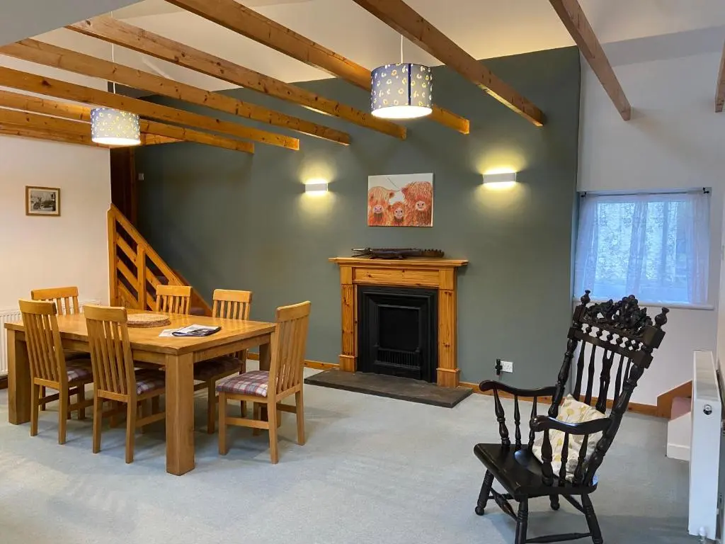 a dining room with a table and chairs and a fireplace at Easter Corrie Cottages in Ballindalloch