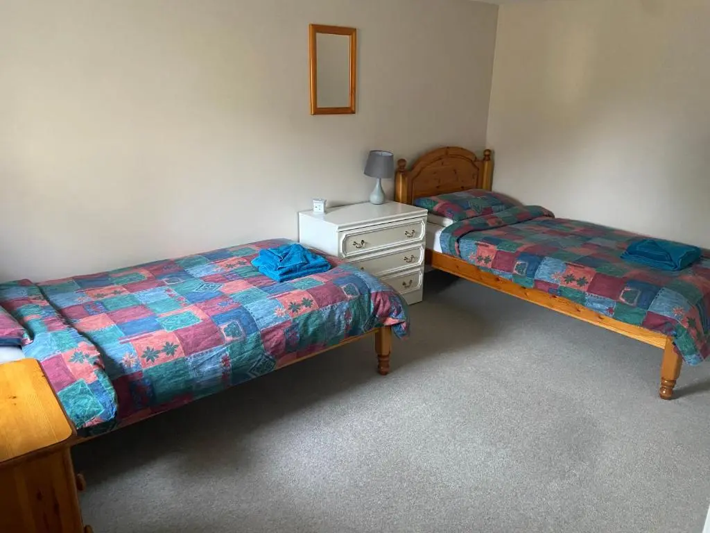 a room with two beds and a dresser in it at Easter Corrie Cottages in Ballindalloch