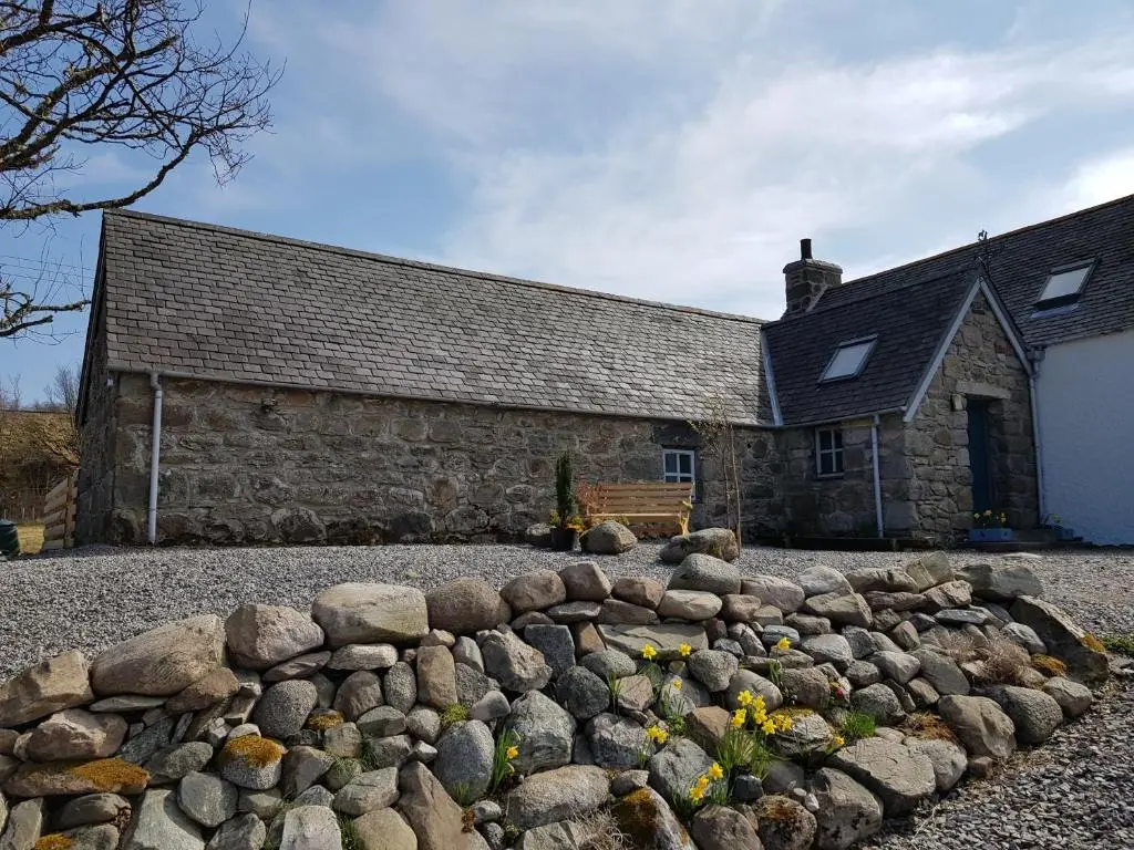 an old stone building with a rock wall in front of it at Jakels Rest in Lairg