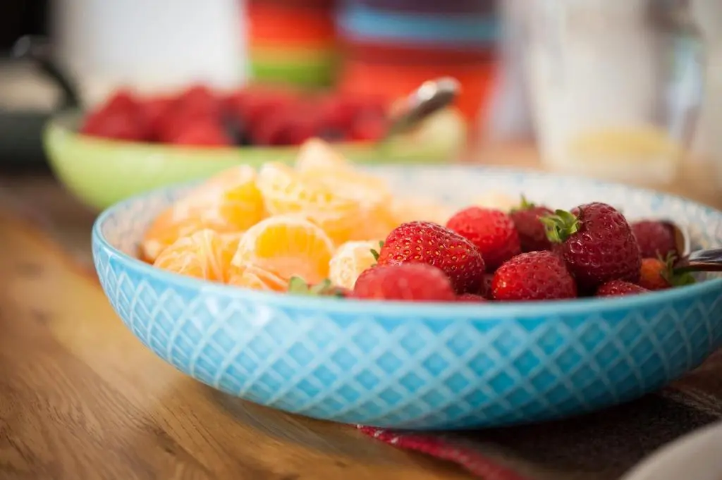 a blue bowl of strawberries and oranges on a table at Kilmore Farmhouse in Drumnadrochit