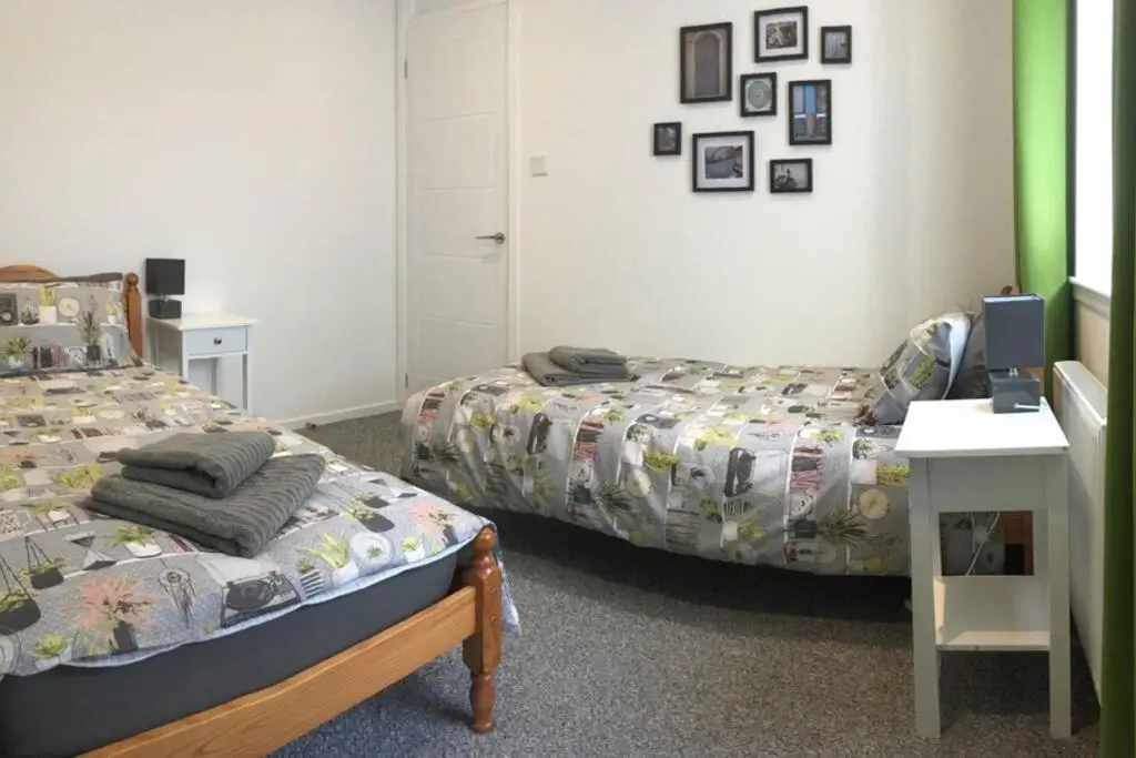 a bedroom with two beds and a table with a desk at Blarmore Apartment Inverness in Inverness