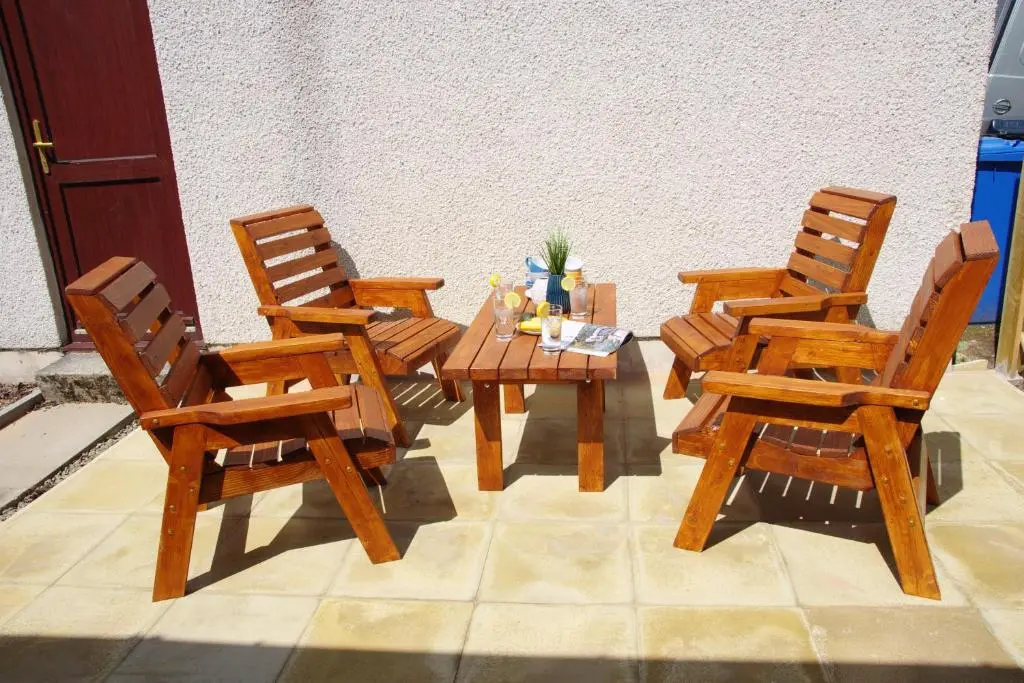 three wooden chairs and a wooden table and chairs at Blarmore Apartment Inverness in Inverness