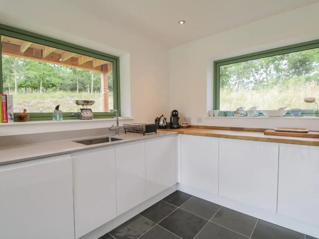 a kitchen with white cabinets and a window at Na Clamhanan in Forres