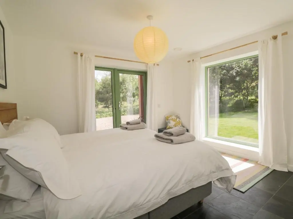 a white bedroom with a large bed and a window at Na Clamhanan in Forres