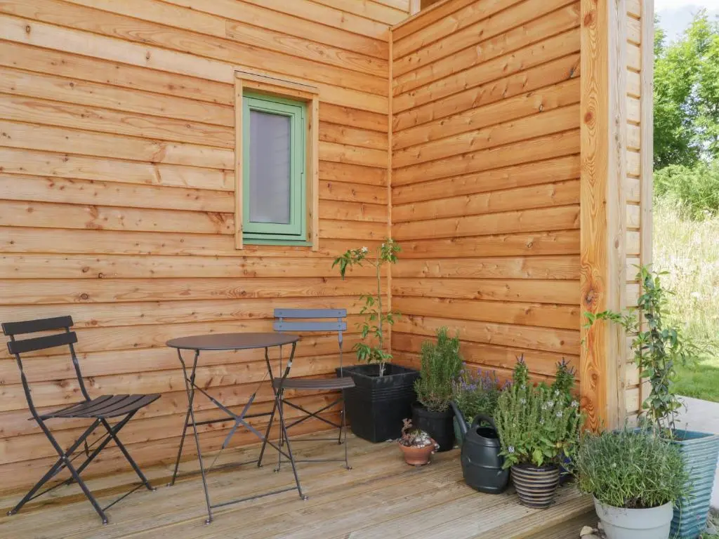 a patio with a table and chairs in front of a wooden wall at Na Clamhanan in Forres